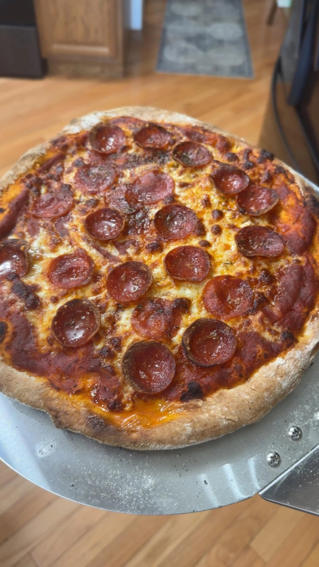 A homemade pepperoni pizza on a metal pizza peel in a home kitchen