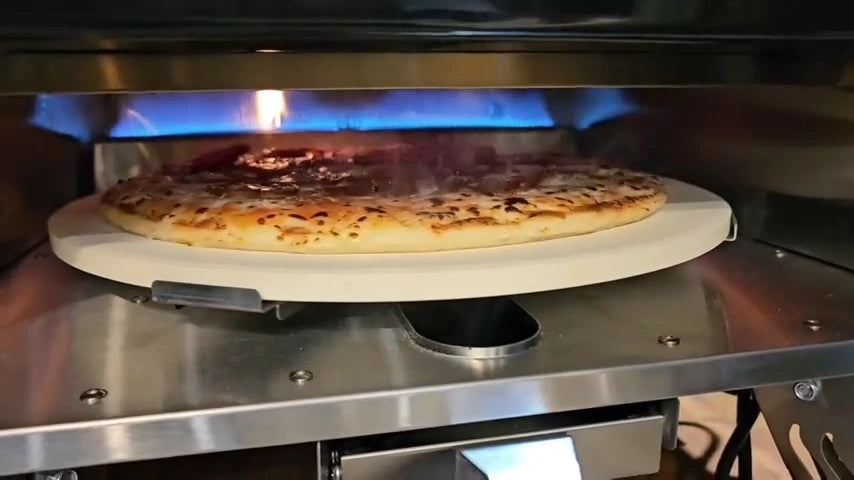 Pizza cooking on a rotating stone with visible blue flames inside the oven